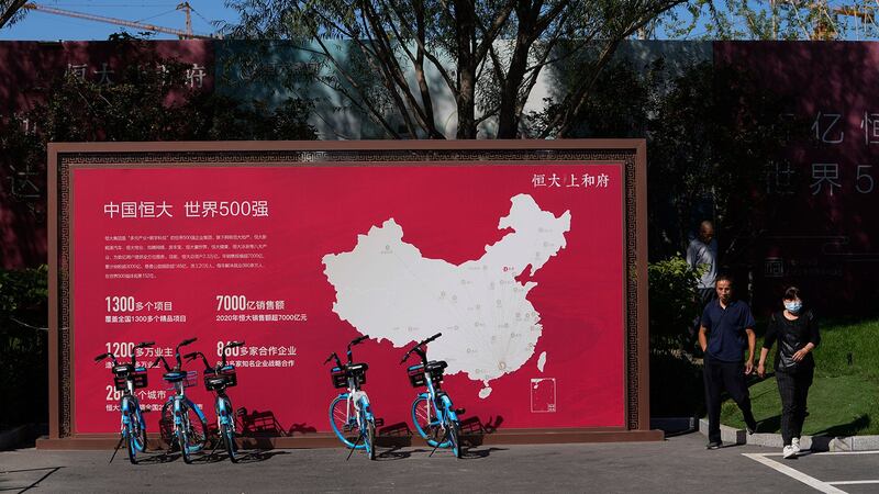 2021 年 9 月 22 日,在北京恒大新住宅开发项目中,人们走过一张显示中国恒大开发项目的地图。(美联社)