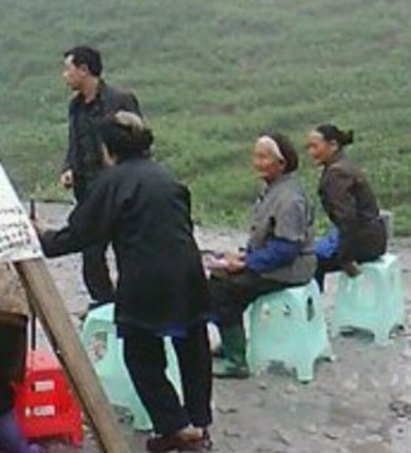 村民抗議道路受嚴重碾壓，民房被震出裂痕，多名老婦坐在公路上與武警對峙。(相片由現場人士提供)