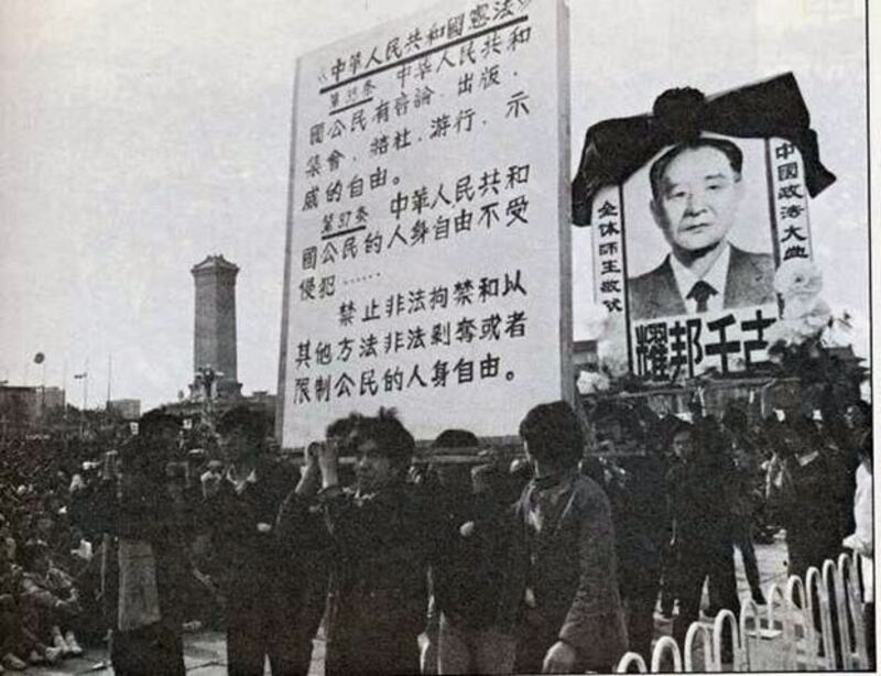 1989年4月22日晨，天安门广场，政法大学的两个大看板很受欢迎，时时被呼唤出来亮相。吴仁华建议制作大看板，刘苏里捐出打家具的木头。胡耀邦遗像是张丽英所画，宪法条文是刘斌书写。（六四档案图）