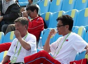 북한 중년 남자 4명이 2010년 11월 18일 광저우 아시안게임 한국과 중국의 야구 준결승 경기가 열린 아오티 야구장에서 경기를 관전하고 있다.