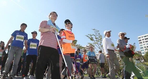 서울 여의도 한강 둔치에서 열린 '서울시각장애인 돕기 마라톤 대회' 5km 코스에 참가한 시각장애인과 가이드러너가 서로의 팔에 안내선을 착용한 채 반환점을 향해 이동하고 있다. 