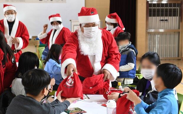 경남 거창군 신원면 신원초등학교 강당에서 산타로 분장한 거창군 관내 사회적기업협의체 관계자들이 학생들과 크리스마스카드 만들기 수업을 마친 후 선물을 나눠주고 있다.