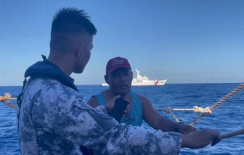 漁民受訪時，中國海警船亦在遠處監視。（菲律賓海岸防衛隊影片截圖）