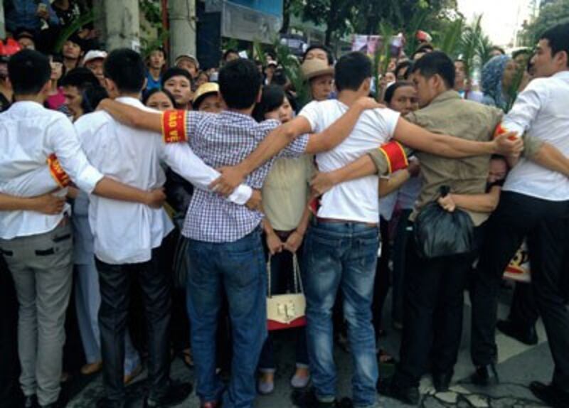 Vietnamese plainclothes policemen form a human chain to prevent protestors from approaching the People's Court in Hanoi, Oct. 2, 2013. Credit: AFP