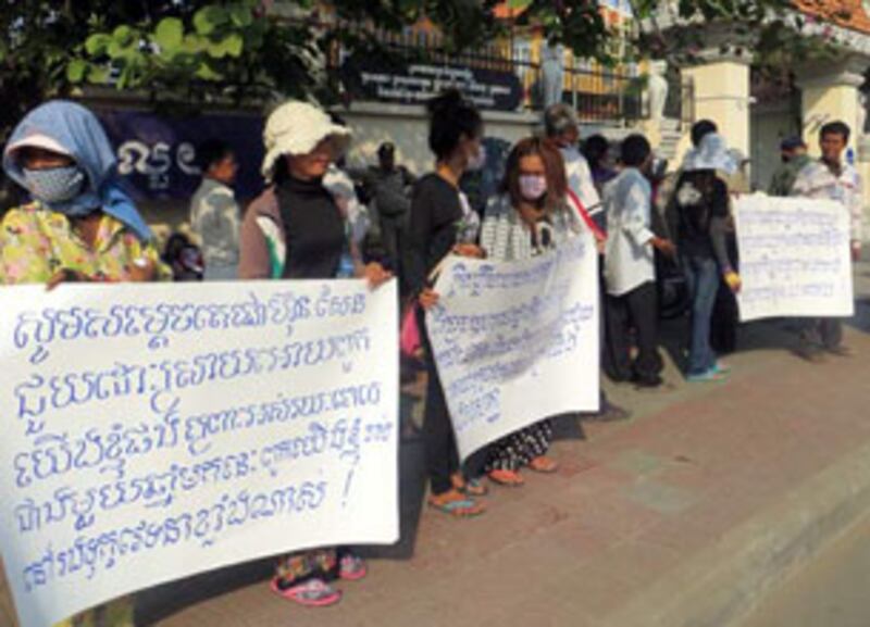 អ្នក​ភូមិ​បុរីកីឡា ឈរ​កាន់​បដា​តវ៉ា​នៅ​ខាង​មុខ​ក្រសួង​មហាផ្ទៃ នៅ​ព្រឹក​ថ្ងៃ​ទី​២១ មករា ឆ្នាំ​២០១៣។