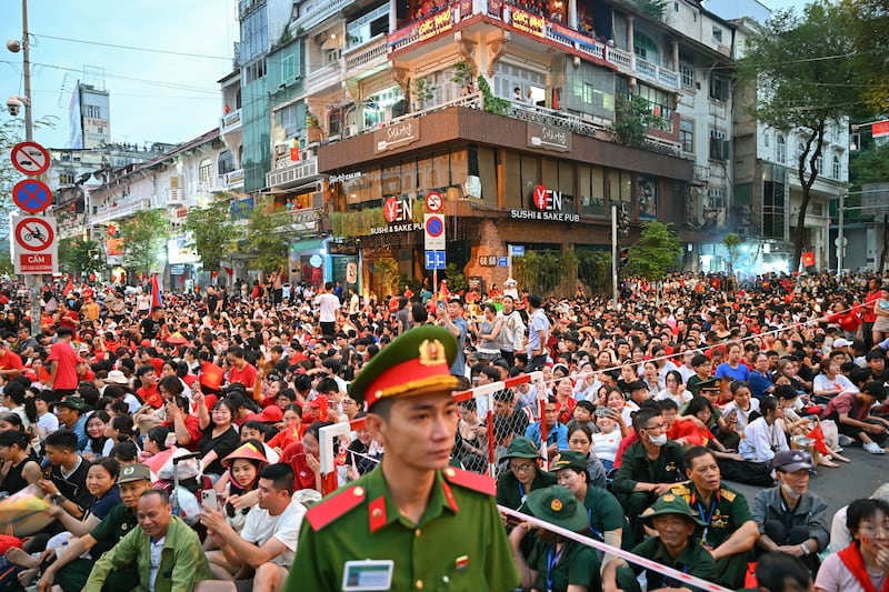 People sit on the sidewalk ahead of a parade marking the 50th anniversary of the fall of Saigon and the end of the Vietnam War, April 30, 2025.
