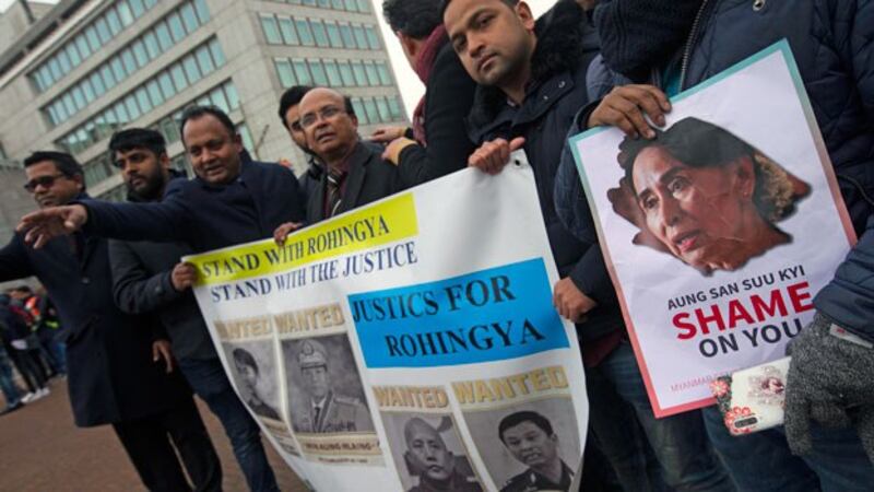 Demonstrators hold signs outside the International Court of Justice where Myanmar's leader Aung San Suu Kyi attended the first day of three days of hearings in The Hague, the Netherlands, Dec. 10, 2019.