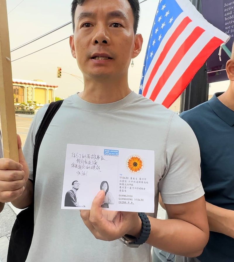 一名活动参加者手持自己写下的明信片(界立建提供)