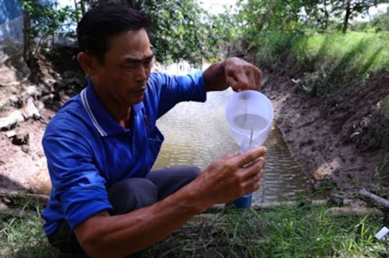 Nông dân Trịnh Hòa Mi đo lượng muối trong nước biển tại trang trại nuôi tôm của gia đình anh ở Sóc Trăng hôm 4/7/2010.