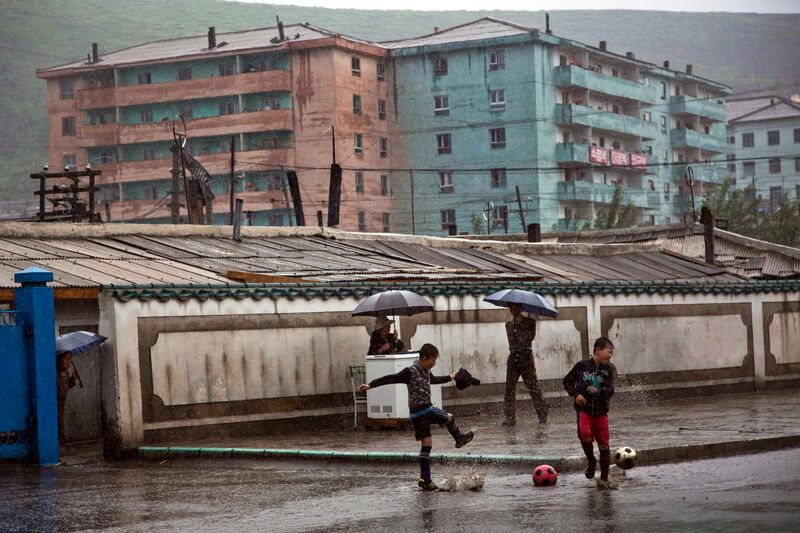 Boys play soccer in front of apartment buildings in the town of Hyesan in North Korea's Ryanggang province, June 16, 2014.