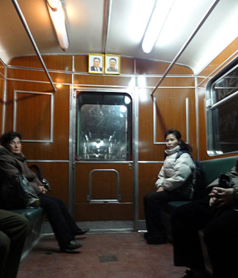 圖片4和10:記者進入站內,對平壤地鐵進行一番體驗。車上乘客稀落,他們都顯得非常安靜。記者還發現,偉大領袖的影響真可謂無所不在,包括每節地鐵車廂,在最高最當眼的位置,一定並排著金日成和金正日的畫像。另外,北韓的電視台也是全天候進行愛國教育,從早到晚都播放著體育節目,宣揚北韓是世界體育強國。