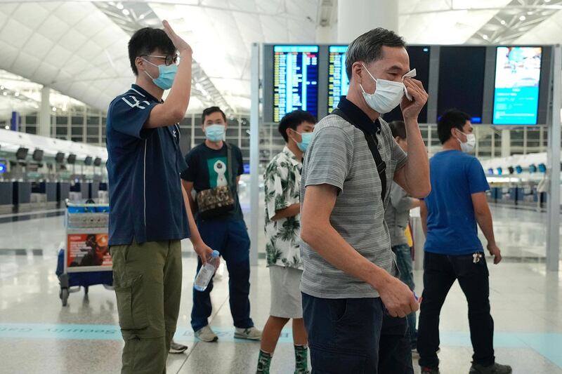 2021 年 6 月 30 日,当他的亲人前往香港机场永久移居英国时,一名男子(右)哭泣 。(美联社)