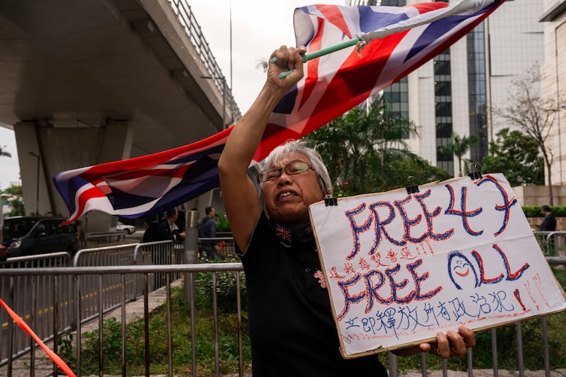 A pro-democracy activist known as "Grandma Wong" protests outside the West Kowloon courts in a cordoned off area set up by police as closing arguments open in Hong Kong's largest national security trial of 47 pro-democracy figures in Hong Kong, Wednesday, Nov. 29, 2023.