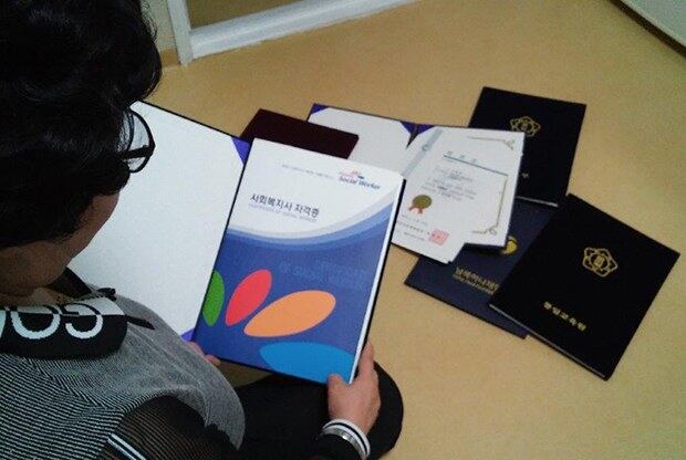 아파트에서 자신의 졸업장과 자격증을 보여주고 있는 모습.