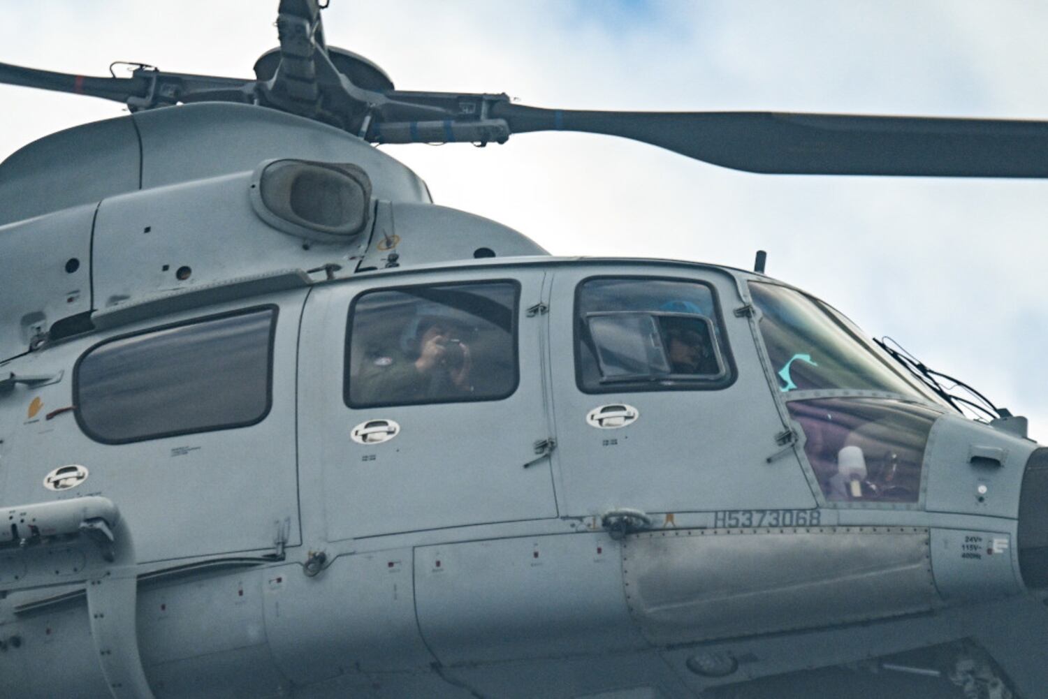A Chinese Navy member takes photos as his helicopter passes within a few meters of a Philippine Bureau of Fisheries and Aquatic Resources aircraft in the South China Sea, Feb. 18, 2025.