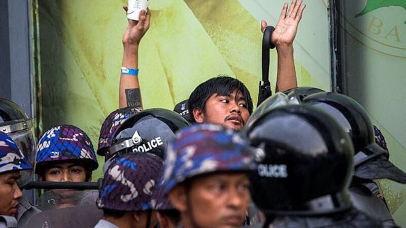 Myanmar police surround a demonstrator during an antiwar protest in Yangon, May 12, 2018.