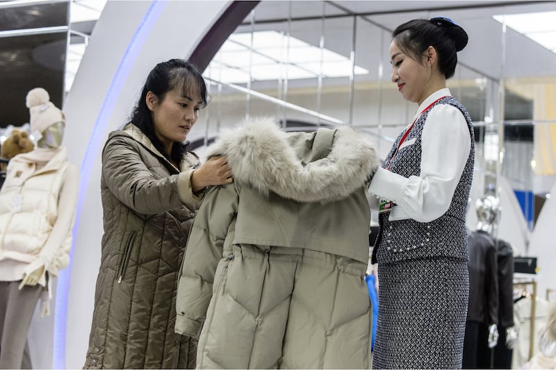 2023년 11월 9일 북한 평양 옥류 전시관에서 열린 가을철 의류 전시회에서 한 북한 여성이 외투를 보고 있다.