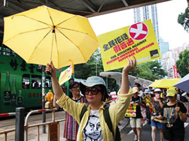 2015年6月14日， 有參與遊行的市民高舉黃傘和標語，反對假普選。(粵語組林靜攝)