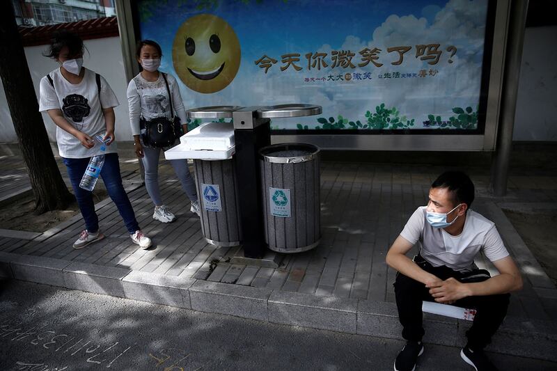 资料图片：2020年5月13日，北京，新型冠状病毒病爆发后，三位青年在前往购物中心寻找工作的公交车站等候。（路透社）