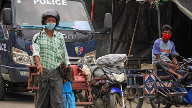 A police officer observes people wearing face masks on a street during a lockdown amid the coronavirus pandemic in Sittwe, capital of western Myanmar's Rakhine state, Aug. 23, 2020.