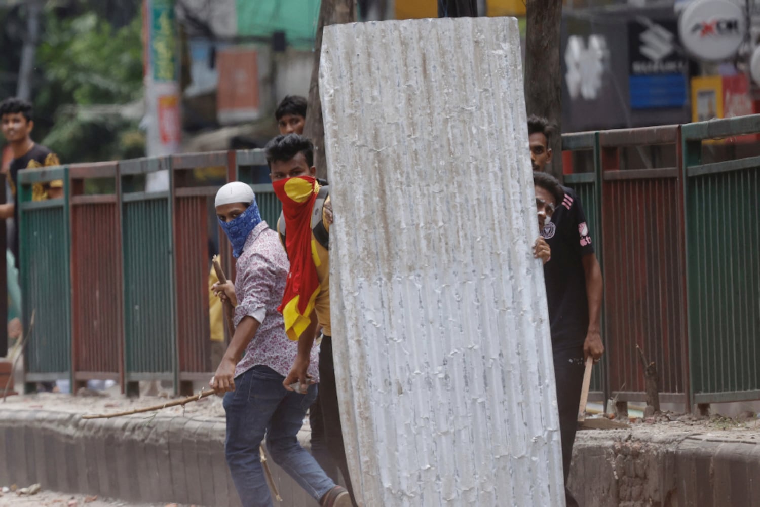 Protesters use a piece of sheet metal as a shield during a clash with Border Guard Bangladesh and police outside the state-owned Bangladesh Television station in Dhaka, July 19, 2024. (Mohammad Ponir Hossain/Reuters)