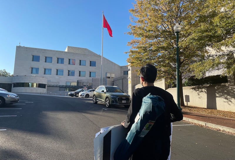 凯文拿着标语走向中国驻美大使馆（记者唐缘媛摄）