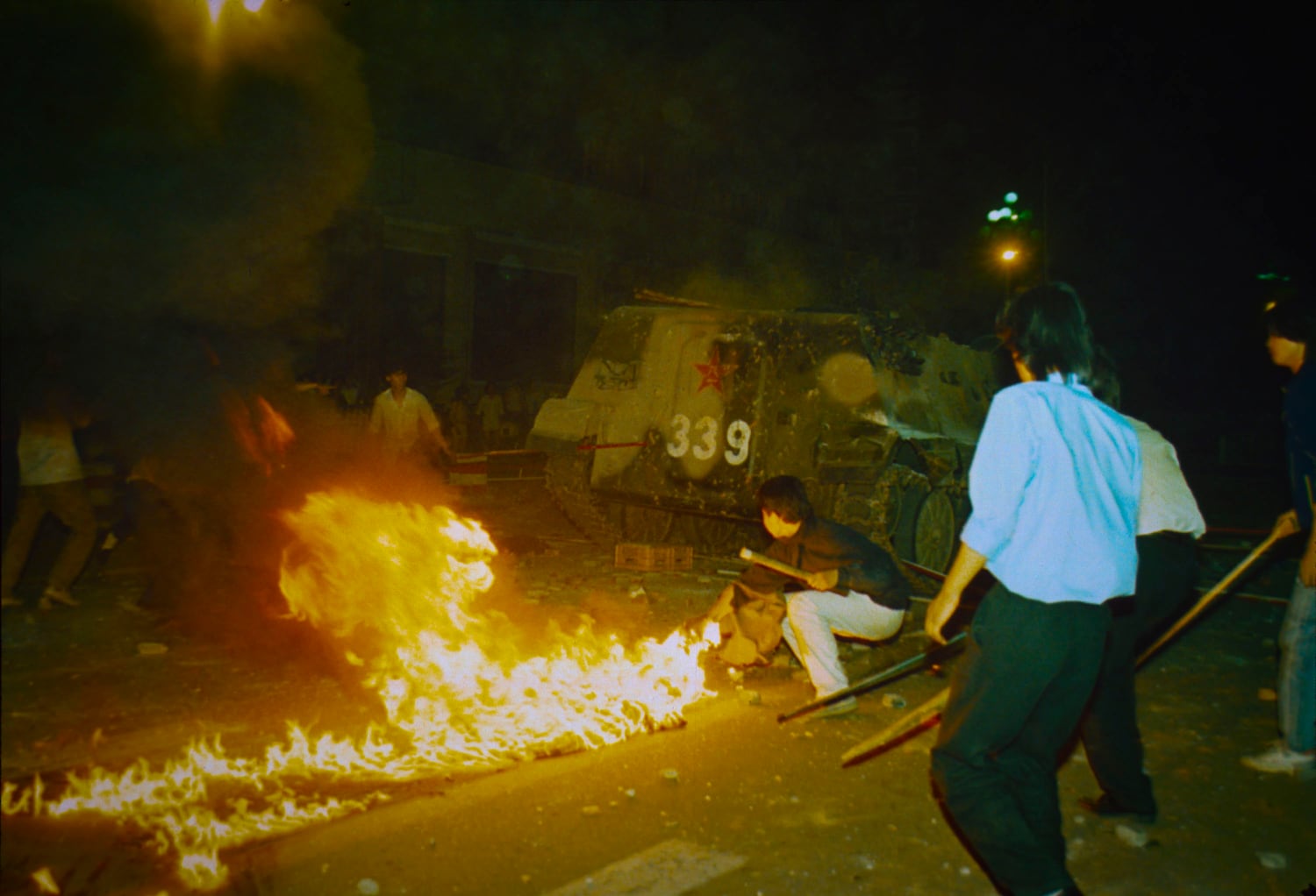 Student protesters put a barricade in front of a burning armored personnel carrier that rammed through student lines, June 4, 1989, at Beijing's Tiananmen Square.