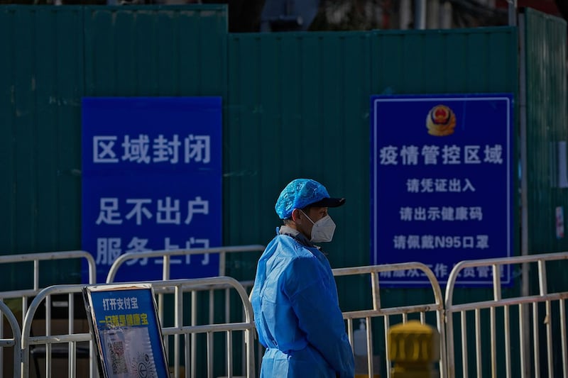 2022年11月13日，北京，一名身穿防护服的工人站在封闭社区。（美联社）