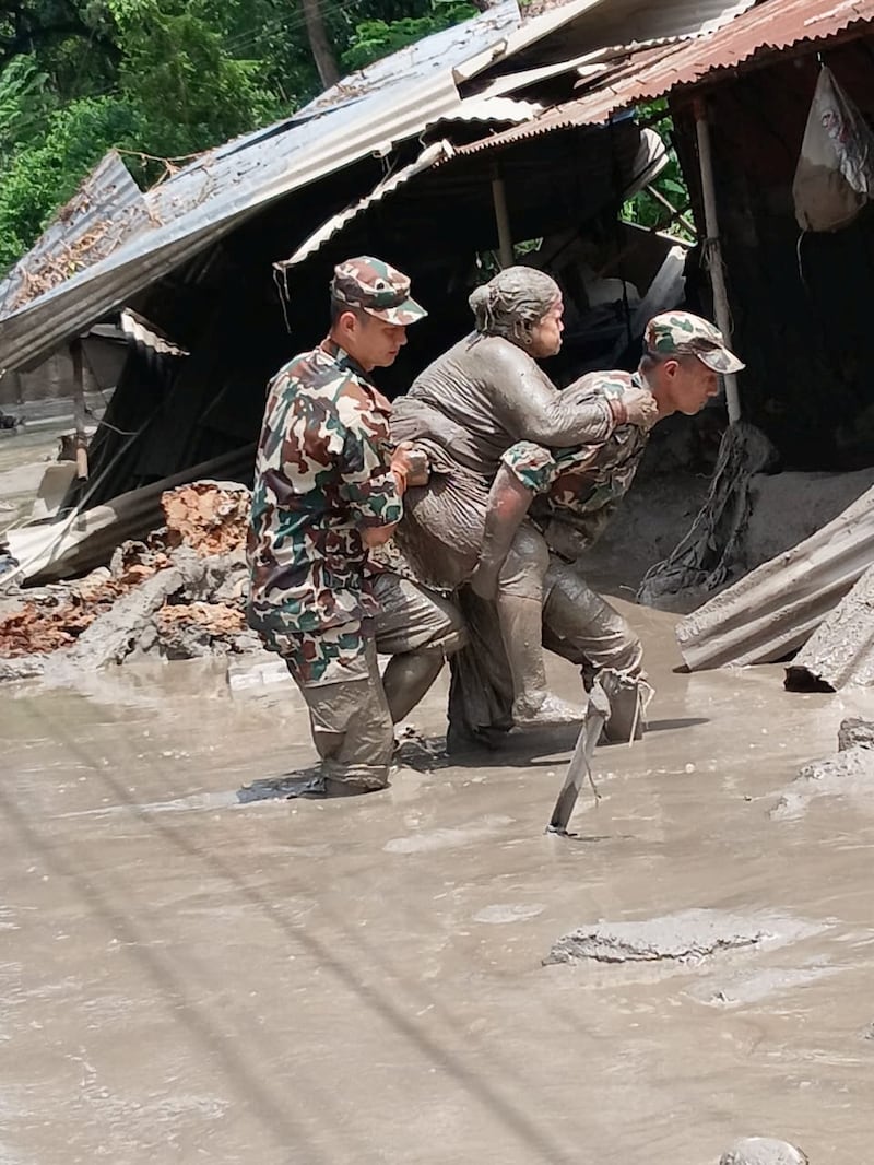 Nepali army soldiers move a survivor following flash floods and a mudslide near the Nepal-Tibet border in Nepal, Aug. 27, 2026.