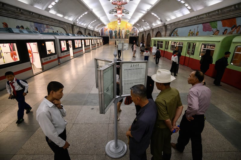 Commuters read a newspaper while waiting for a train at a newsstand in a subway station in Pyongyang on June 19, 2019.