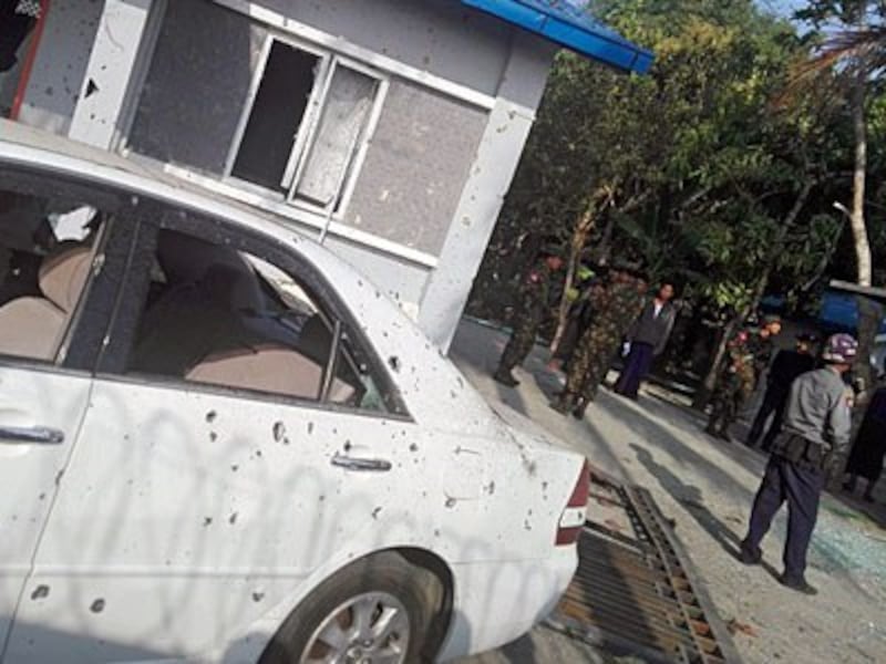 Members of the Myanmar military stand guard next to a damaged car after an early morning explosion in the compound of the state government secretary's home in Sittwe, capital of western Myanmar's Rakhine state, Feb. 24, 2018.
