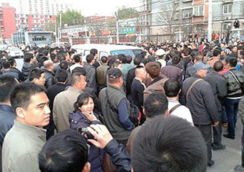 2013年4月24日,北京豐台區一地鐵站出口,發生城管毆打違規三輪車伕事件,上百途人不值所為圍堵城管執法車討說法。(當地市民攝)