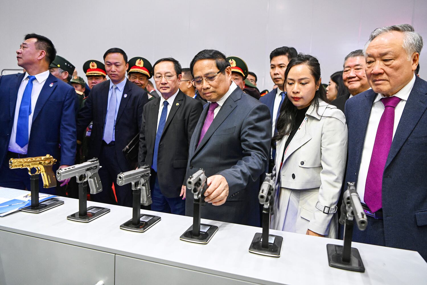 Vietnam's Prime Minister Pham Minh Chinh, center, checks out a Turkish-made pistol during the Vietnam 2024 International Defense Expo in Hanoi on Dec. 19, 2024.