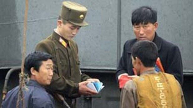 북한 국경경비대원들이 신의주에서 주민들을 검열하고 있다.