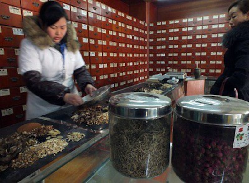 A pharmacist dispenses traditional Chinese medicine at a store in Yichang city, Hubei, Jan. 9, 2013. Photo credit: ImagineChina.