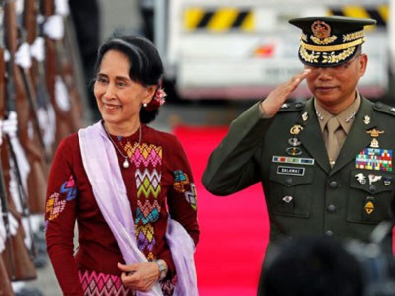 Myanmar State Counselor Aung San Suu Kyi walks with a Filipino military officer upon her arrival in Pampanga province, the Philippines, to attend the Association of South East Asian Nations summit and related meetings in the capital Manila, Nov. 11, 2017.