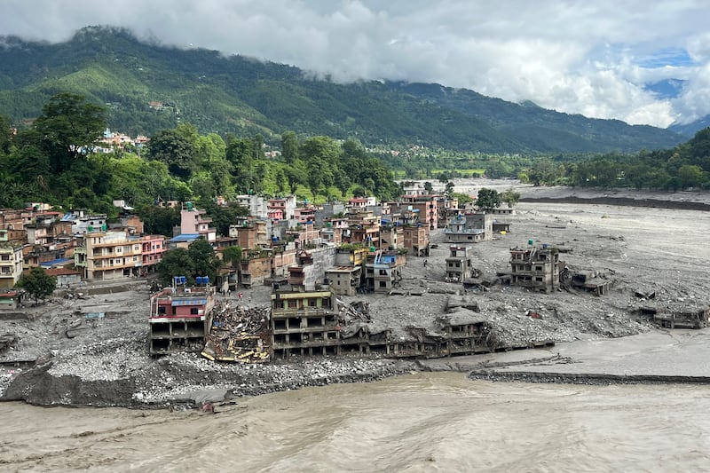 An aerial view shows a torrent of muddy water surging past houses and through the Trishuli River in the aftermath of flash floods at Trishuli Center in Nepal's Nuwakot district on Sept. 1, 2026.