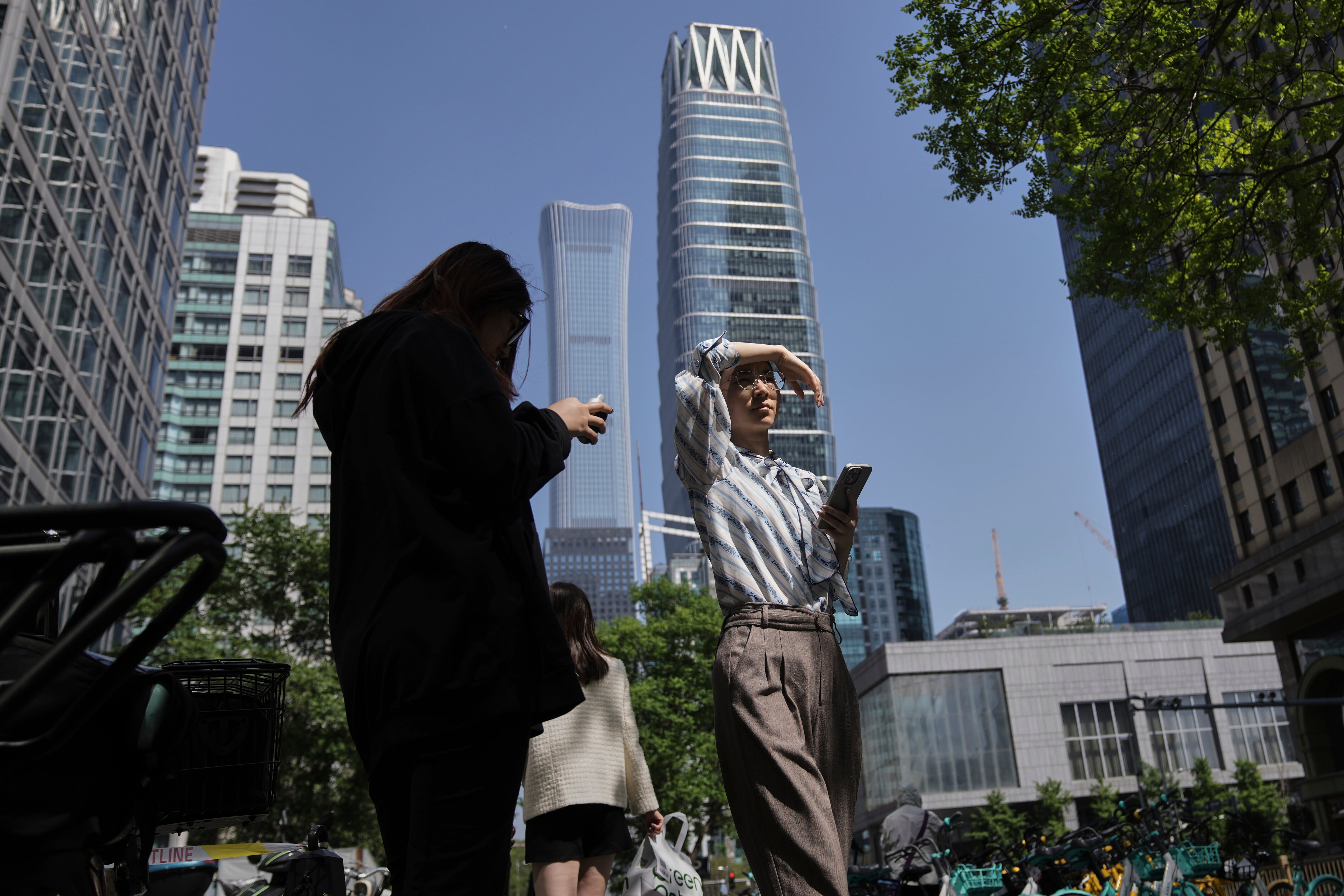 Women walk past office buildings during their lunch break at the Central Business District, in Beijing, Monday, April 28, 2025. (AP Photo/Andy Wong)