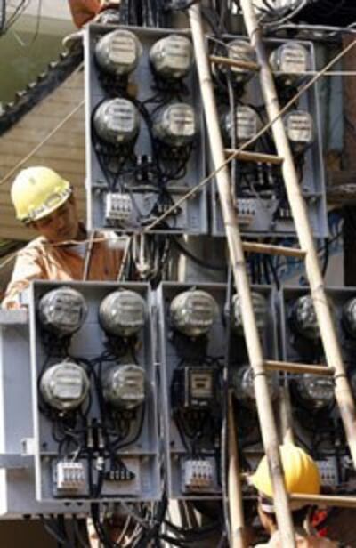Công nhân ngành điện đang kiểm tra đồng hồ điện tại Hà Nội. AFP PHOTO. 