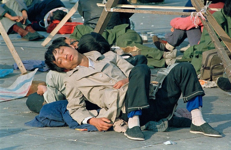 1989年5月23日,两名学生在天安门广场上相互靠着休息。(美联社)