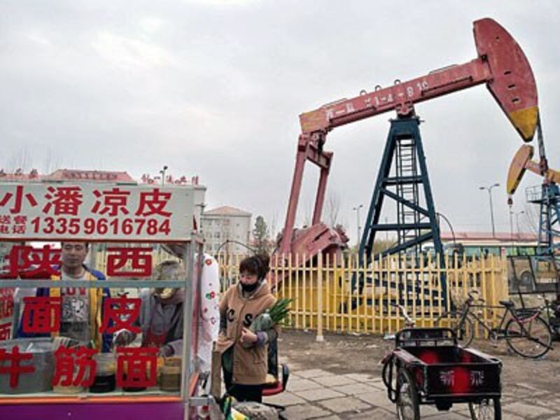 A local resident buys noodle soup from a cart next to an oil derrick in Daqing, China's northern Heilongjiang province, May 2, 2016.