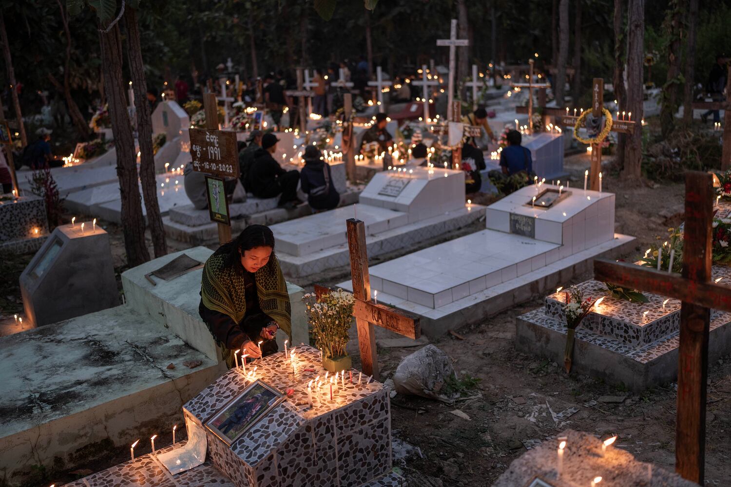 A woman lights candles at a martyrs cemetery to commemorate the fighters who died fighting Myanmar's military in Demoso, Kayah state, Nov. 2, 2024. (RFA)