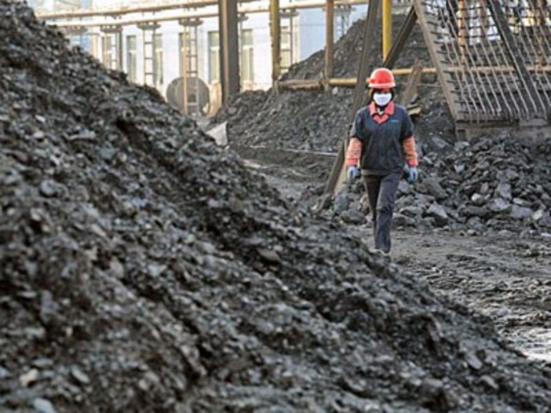 A Chinese worker walks past piles of coal in a coalyard at a mine in Huaibei, eastern China's Anhui province, Nov. 7, 2016.