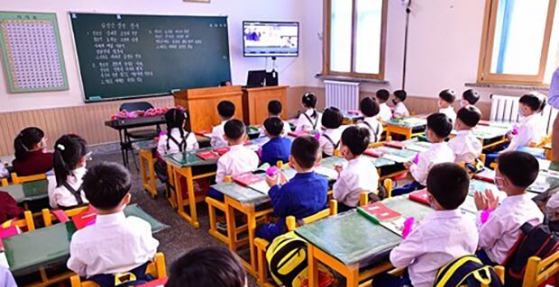 평양시 대동강구역 옥류소학교에서 마스크를 쓴 어린이들이 TV로 개학식을 지켜보고 있다. 교실 칠판에는 '김정은 장군 찬가'가 필기돼 있다.