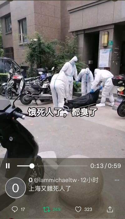 上海一居民小區傳出「餓死人」消息，防護人員抬著一黑色長形包裹。（網絡圖片）