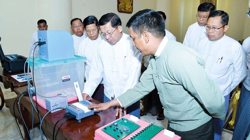 အီလက်ထရွန်နစ် မဲပေးစနစ်အသုံးပြုပုံနှင့် စက်ပိုင်းဆိုင်ရာများကို ကြည့်ရှုနေသည့် စစ်ကောင်စီခေါင်းဆောင် ဗိုလ်ချုပ်မှူးကြီးမင်းအောင်လှိုင်အား ၂၀၂၃ ခုနှစ် ဖေဖော်ဝါရီလ ၉ ရက်နေ့က တွေ့ရစဉ်။ (Photo: Myanmar Military)