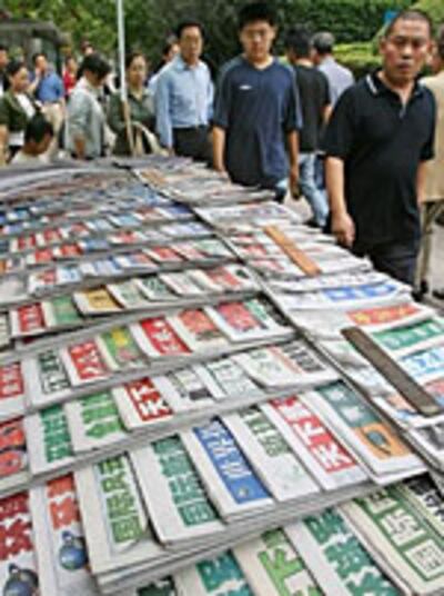 Sept. 14, 2006: Chinese shoppers walk past a kiosk selling domestic Chinese newspapers at People's Square in Shanghai. Photo: AFP/Mark Ralston
