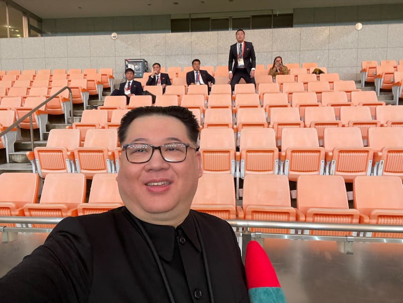 굳은 표정으로 앉아 있는 김일국 북한 체육상(가운데)과 하워드 X 씨를 향해 소리를 지르려 일어선 북한 측 관계자를 배경으로 셀카를 촬영 중인 하워드 X 씨.