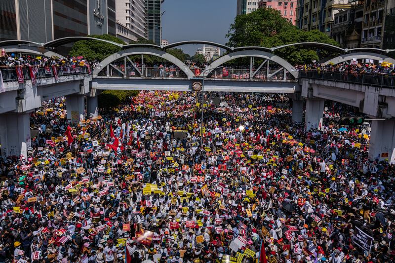 Protesters chant slogans and wave flags during an anti-coup protest at Sule Square on February 17, 2021 in Yangon, Myanmar.