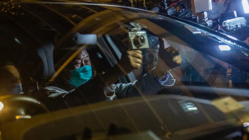 黎智英被羁押41小时后取保候审,他坐在车里对支持群众和媒体比出大姆指。(法新社)